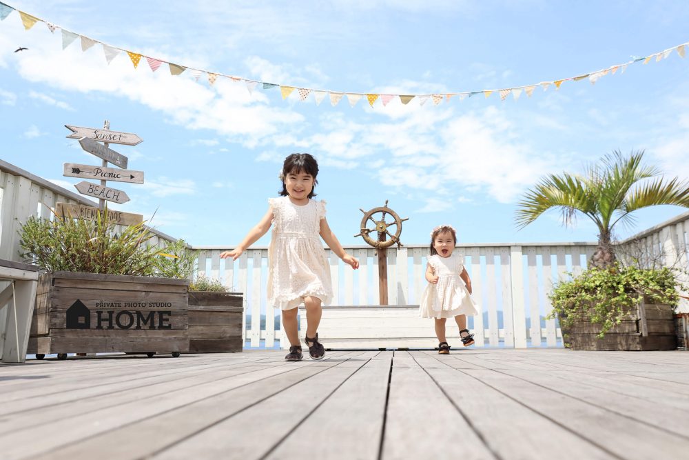 子供写真スタジオStudioHome横須賀店の3Fデッキで撮影した青空の下走っている姉妹写真。